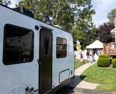 Trailer parked on the backyard with people celebrating a birthday on the background.
