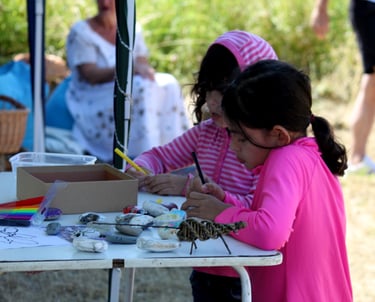 2 children decorating pebbles