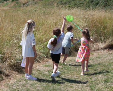 Children running through field with a butterfly net