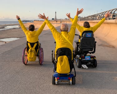 Three wheelchair users enjoying an accessible seaside promenade.