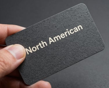 A close up of a hand holding a high-quality textured business card. Slate color with off white typography. North American / International style.
