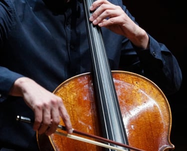 A close-up of a professional cellist’s hands during a performance. The lighting is elegant and dramatic, emphasizing the texture of the instrument and the precision of the musician, with steel blue and dark navy blue tones.
