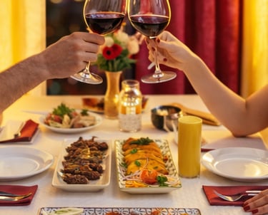 A couple toast with red wine glasses over a table of gourmet appetizers during a romantic dinner.