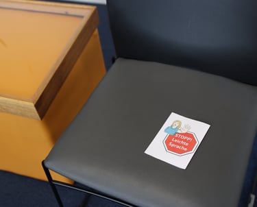 Die Sitzfläche eines Stuhls auf dem ein "Stopp - Leichte Sprache" Zettel liegt.