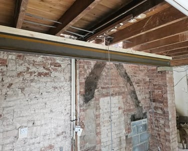 A structural steel RSJ beam installed against a red brick wall during a home renovation.