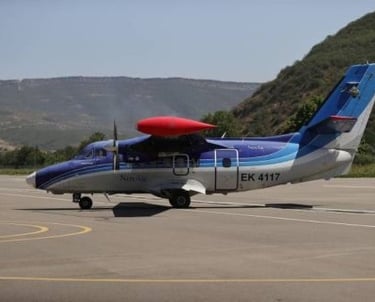A blue and white Nov Air Let L-410 Turbolet airplane taxiing on an airport runway.