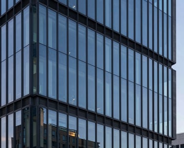A minimalist architectural detail of a high-tech North American office building at dusk. The glass reflects steel blue and slate navy tones, symbolizing modern efficiency and the solid foundation of digital tools.