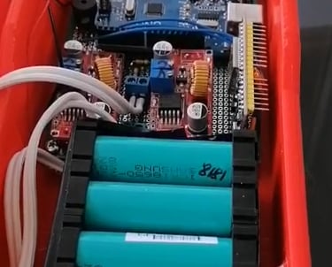 Internal view of an Arduino microcontroller project with gas sensors and 18650 lithium batteries in a red 3D printed case.