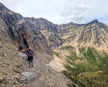 Hikers walking along a narrow cliff section on the Crypt Lake Trail in Waterton Lakes National Park.