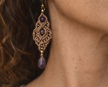 Aretes macramé hechos a mano con piedras de amatista morada usados por una mujer.