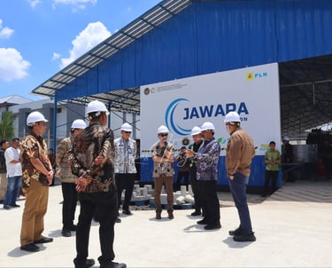 Officials in hard hats visiting the JAWARA PLN industrial facility for a sustainable energy project inspection.