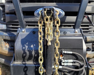 a close up picture of the front of a truck with chains for a plow blade