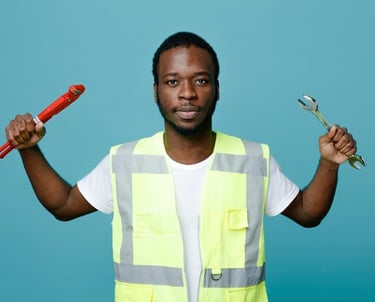 Plombier professionnel de Yaoundé portant un gilet de sécurité et tenant une clé à molette.