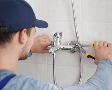 Plumber repairing a leaking shower tap, professional leaking shower repair service Auckland