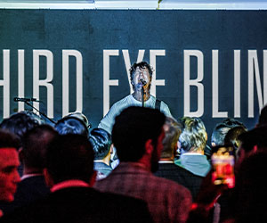 a man standing in front of a large sign that says third eye blind