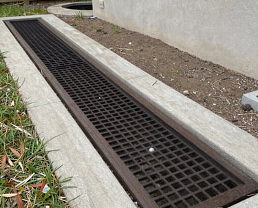 A technician carefully installing a new drain field in a green backyard.