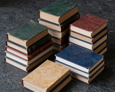 A curated collection of vintage books and modern journals stacked on a dark stone surface. The composition is artistic and clean, evoking a sense of literary history and modern storytelling expertise.