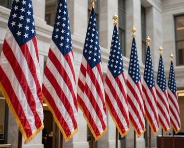 A photograph capturing a row of North American flags standing in a professional lobby of a federal building. The composition uses a low angle to convey authority, with the colors of dark blue and white dominating the clean, polished stone background.