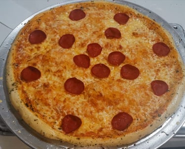 Pizza de pepperoni recién horneada con queso mozzarella fundido, sobre una bandeja redonda de metal.