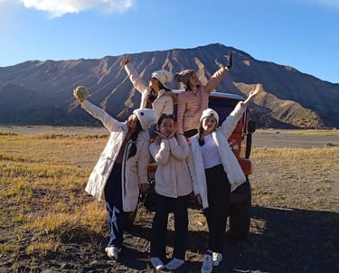 foto sekelompok wanita berpose di depan jeep dengan latar belakang gunung bromo