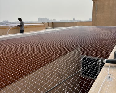 Wide shot of an open balcony area fitted with pigeon safety nets under bright sunlight.