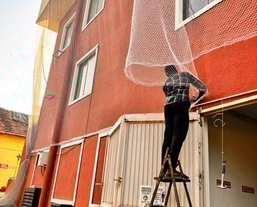 Wide shot of a high-rise Mumbai apartment balcony secured with pigeon safety nets.