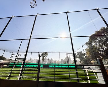 A vibrant cricket practice net installed on a sunny terrace in Mumbai.