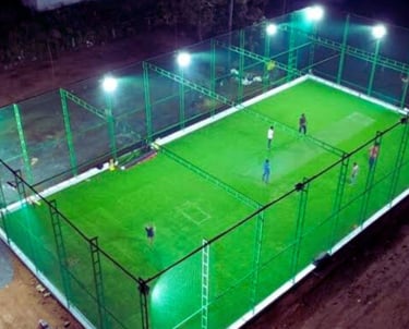 A freshly installed sturdy sports net enclosing a rooftop cricket pitch under a clear blue sky.