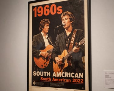 A close-up photograph of a vintage 1960s concert poster on a gallery wall with elegant lighting in a South American museum.