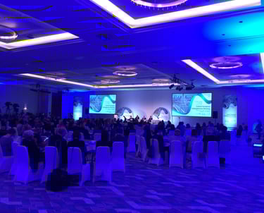 Medical professionals attending the Central European Schizophrenia Meeting in a large blue-lit conference hall.