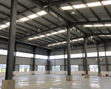 Steel warehouse structure in mid-construction showing heavy steel beams and concrete foundation.