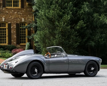 A side profile shot of a silver and black 1958 MG MGA Roadster in an elegant English courtyard