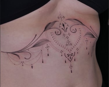Elegant ornamental sternum tattoo with fine line mandalas, hanging beads, and botanical leaf details.