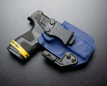 Black semi-automatic handgun secured in a blue Kydex IWB concealed carry holster with a belt clip.