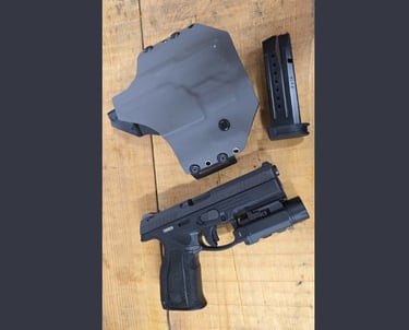Steyr A2 MF handgun with tactical light, gray Kydex holster, and 9x19 magazine on a wood surface.