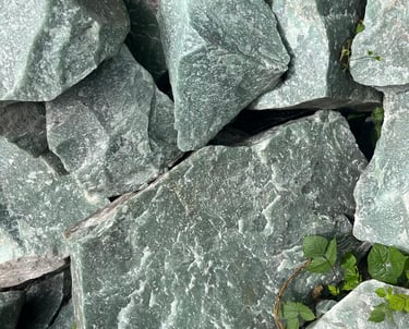 Rochas brutas de quartzo aventurina verde e minerais naturais em uma formação cristalina irregular.