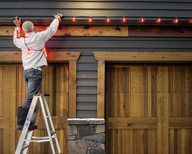 Installer taking down Christmas lights along a home roofline