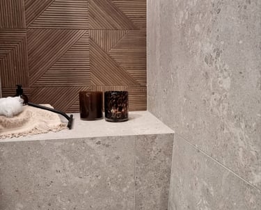 Modern bathroom shower featuring gray terrazzo wall tiles and a brown geometric wood-look accent wall.