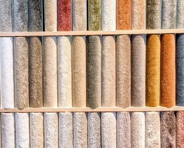 A wall display of colorful carpet samples and rug swatches in various textures and neutral tones.