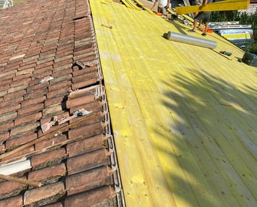 Des couvreurs professionnels installant de nouvelles planches de volige en bois et des tuiles en ter