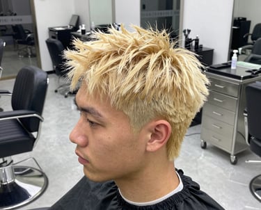 A stylist carefully applying color to a client's hair in a bright, cozy salon space.