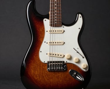Close-up of a handcrafted Stratocaster guitar showing detailed wood grain and metal hardware under warm lighting.