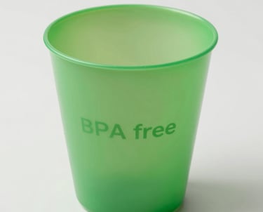 A refreshing iced drink in a transparent cafecup cup with condensation droplets, set against a sunny outdoor cafe background.