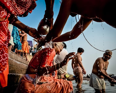 An elderly woman gets playful help from her family in ritual with the Ganges River in Varanasi.