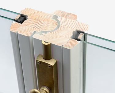 Cross-section of a double-glazed timber window frame with brass hardware and thermal insulation.