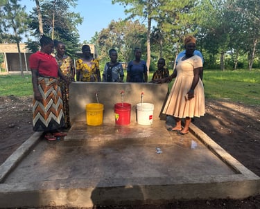 African women standing around a community water tap station with buckets for clean water access.