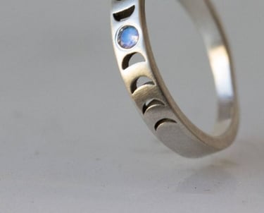 Anillo de fase lunar de plata con una piedra lunar azul y diseños de ciclo lunar grabado