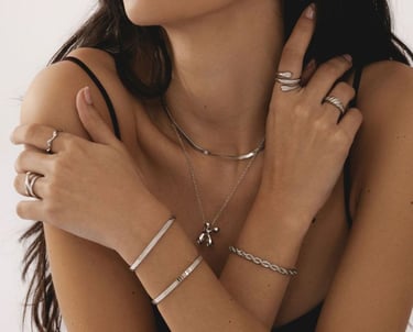 Mujer que usa joyas de plata en capas, incluidos collares, anillos y brazaletes para una apariencia 