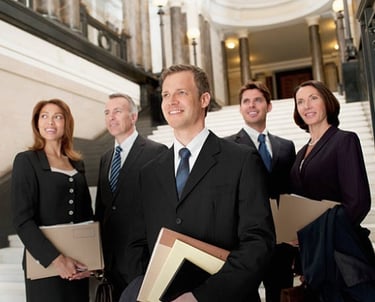 Professional lawyers and business executives in formal suits standing in a corporate building lobby.