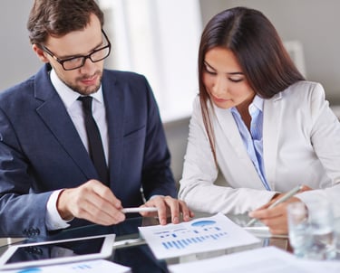 Professional business colleagues analyzing financial data charts and marketing reports in a bright office.